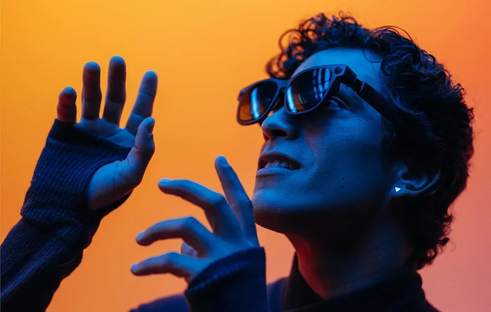Žmogus naudojasi XR akiniais oranžiniame fone