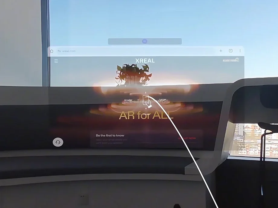 Augmented reality view showing a browser with the XREAL website displayed over a desk with a window in the background.