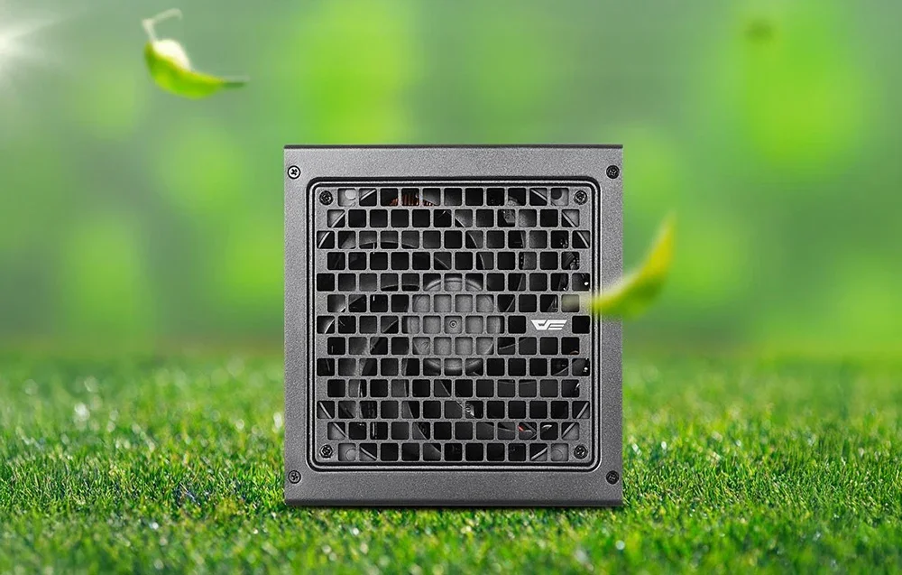 Juodas kompiuterio maitinimo blokas su ventiliaciniu tinkleliu ant dirbtinės žolės